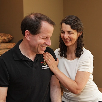 Laura Yedwab, a Kirkland Feldenkrais practitioner, gently raising a fully clothed client's arm as the client lies on the table during a Feldenkrais lesson.