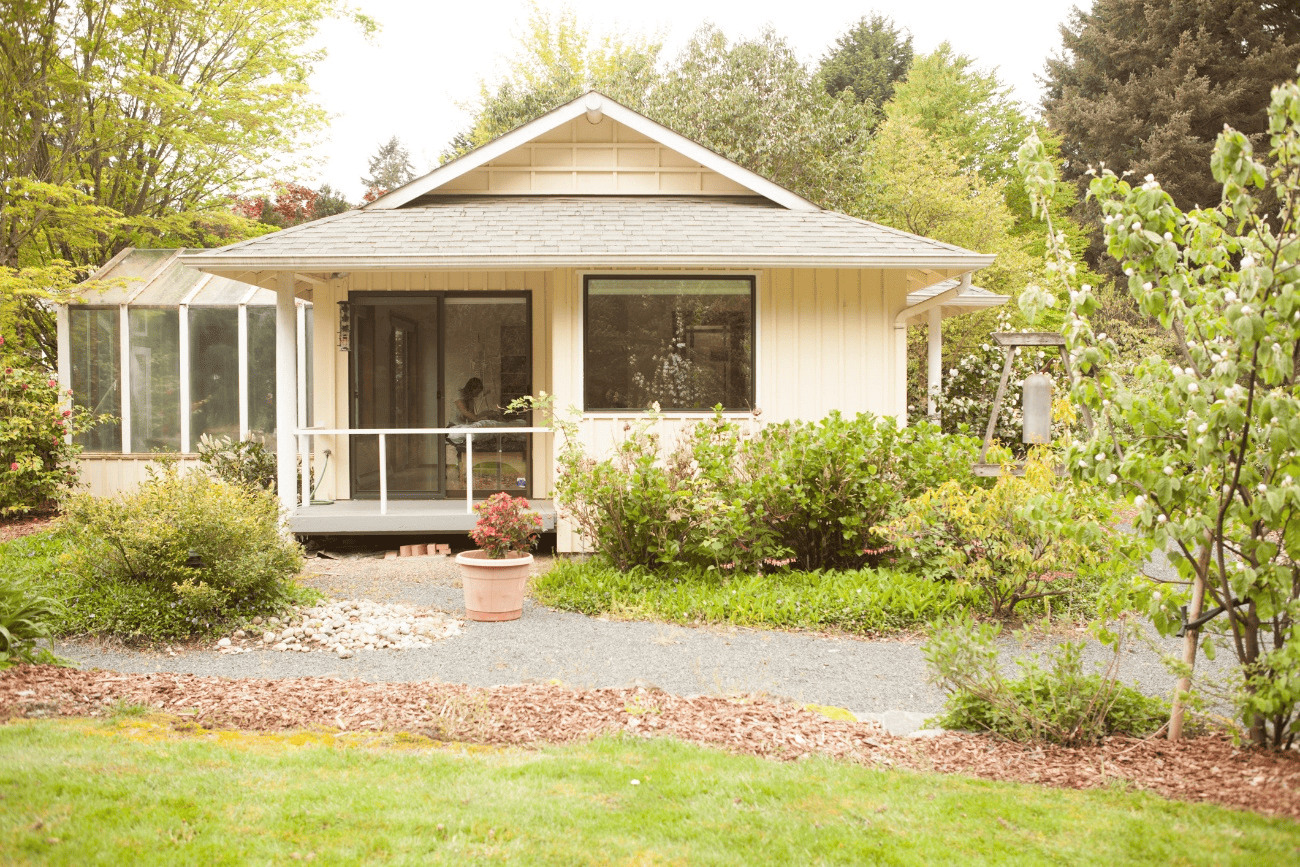 Picture1 The exterior of Laura Yedwab's Feldenkrais studio in Kirkland, a yellow cottage with garden beds and a gravel path