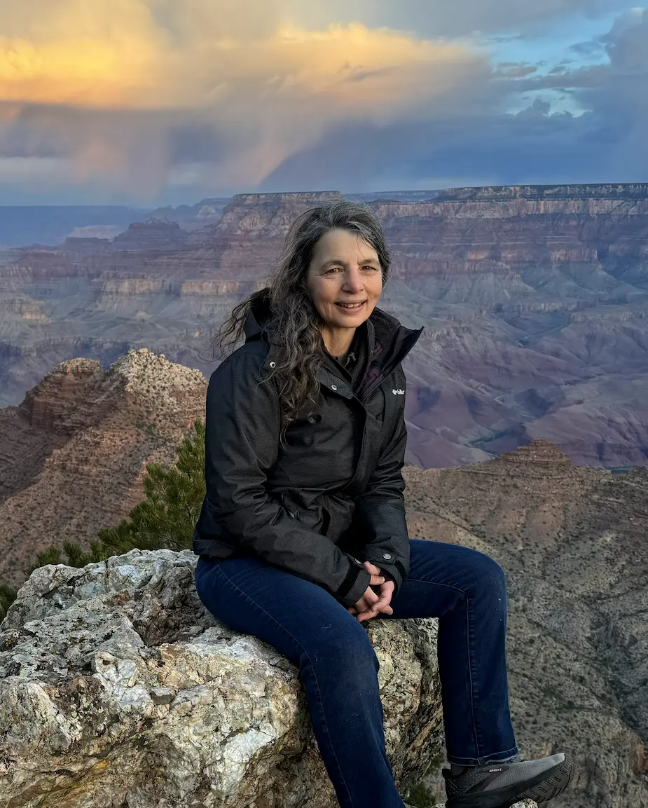 Laura Yedwab sitting on a rock at the Grand Canyon rim at sunrise