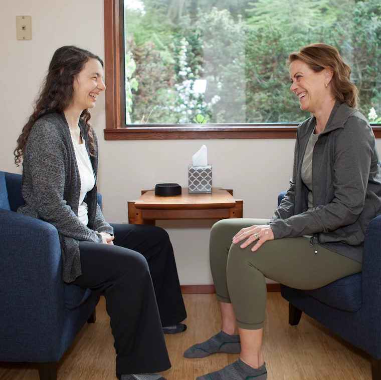 Laura Yedwab and a client sitting in armchairs in her Kirkland studio, talking